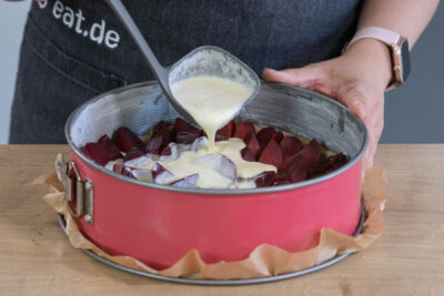 Schmand auf dem Pflaumenkuchen verteilen