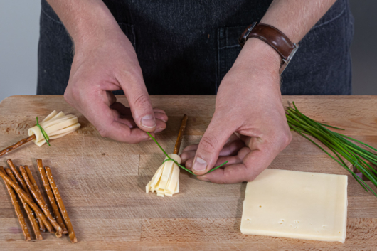 Käse mit Schnittlauch an die Salzstange binden