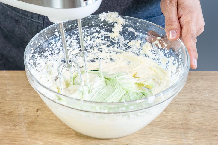 Buttercreme mit Butter, Puderzucker und grüner Lebensmittelfarbeaufschlagen
