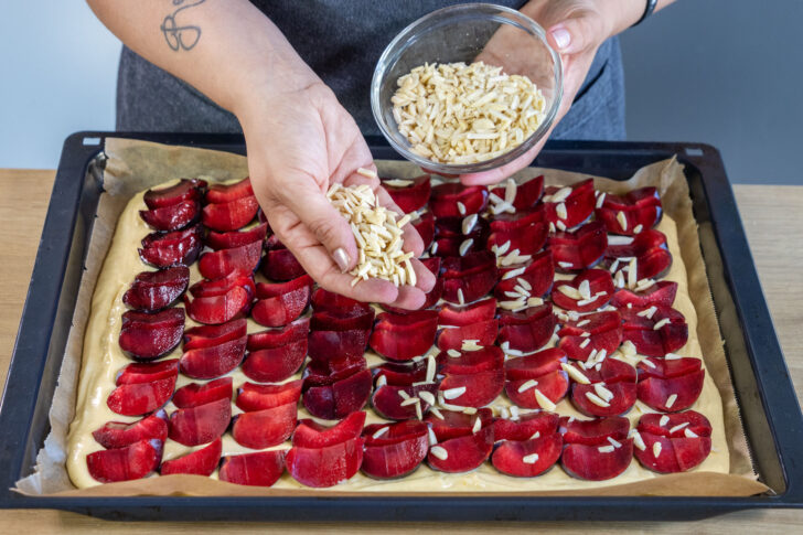 Mandeln über dem schnellen Pflaumenkuchen vom Blech streuen