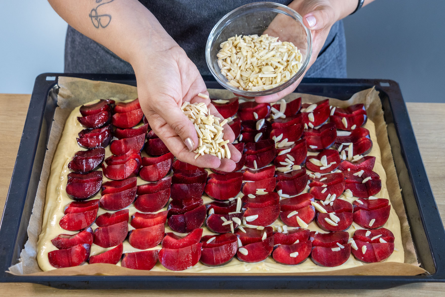 Mandeln über dem schnellen Pflaumenkuchen vom Blech streuen