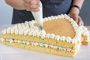 weiße Cremetupfen auf die Schultüten Torte spritzen