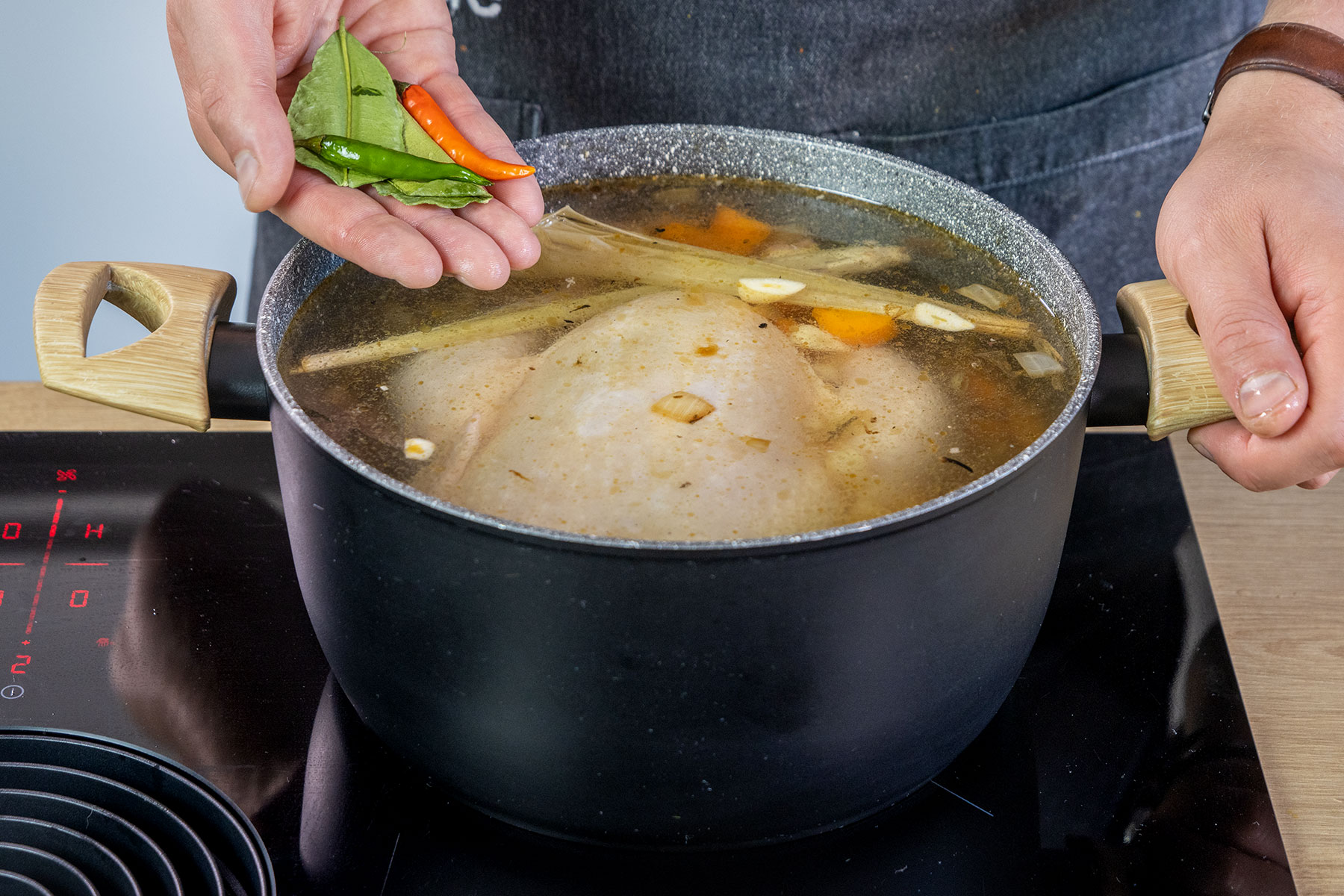 Limettenblätter und Chili in die Suppe geben