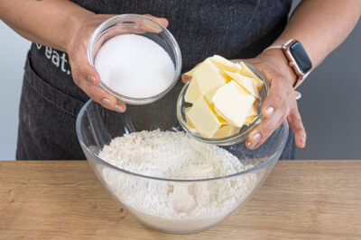 Zucker und Butter zum Mehl geben