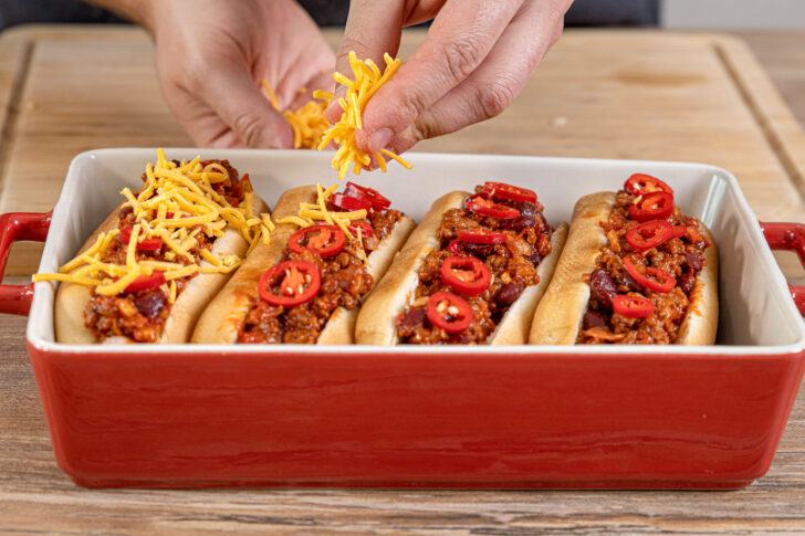 Käse auf Chili Cheese Hot Dog verteilen