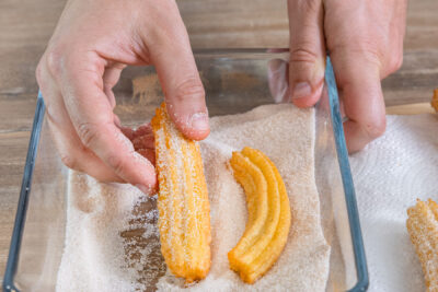 Churros in Zimt und Zucker wälzen