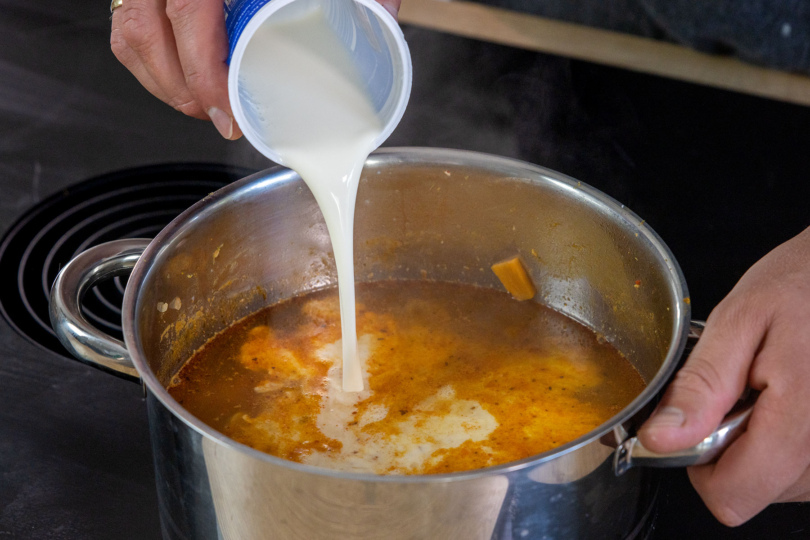 Sahnen zur cremige Kürbis-Süßkartoffel-Suppe gießen