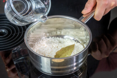 Lorbeerblatt und Wasser zu dem Reis geben