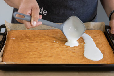 Guss auf dem fluffigen saftigen Zitronenkuchen verstreichen