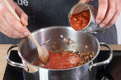 geghackte Tomaten zu den Zwiebeln geben