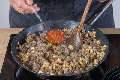 Tomatensoße zum Hackfleisch geben