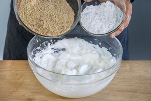 gemahlene Haselnüsse und Zucker zu dem Eiweiß geben