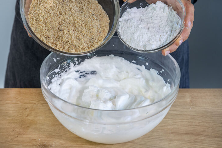 gemahlene Haselnüsse und Zucker zu dem Eiweiß geben