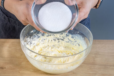 Zucker und Vanillezucker zur aufgeschlagenen Butter geben