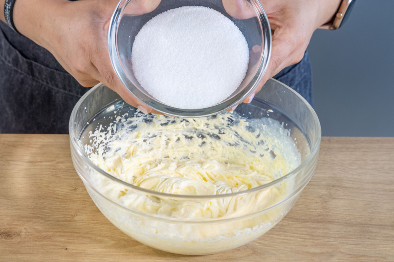 Zucker und Vanillezucker zur aufgeschlagenen Butter geben
