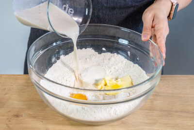 Hefemilch zu dem Ei, Butter und Mehl in die Schüssel gießen