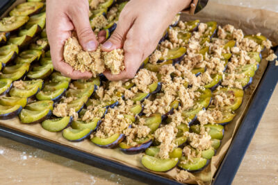 Klassischen Zwetschgenkuchen mit Streusel bestreuen