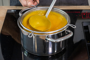 Kürbissuppe durch ein Sieb geben