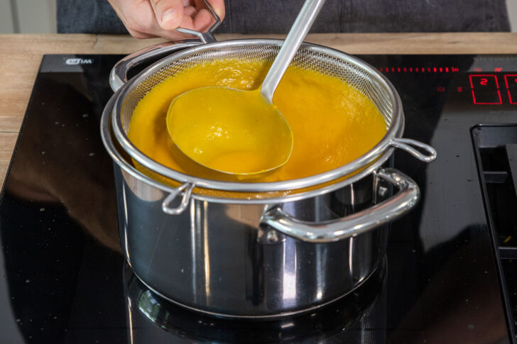 Kürbissuppe durch ein Sieb geben