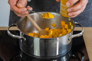 Currygewürz in den Topf geben