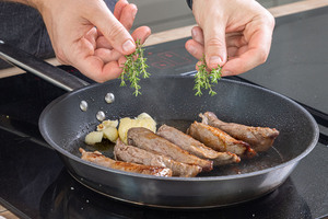 Lammfleisch in der Pfanne braten und Kräuter dazugeben