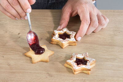Marmelade auf die Mürbeteigplätzchen geben