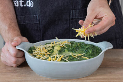 Spinatauflauf mit Käse bestreuen