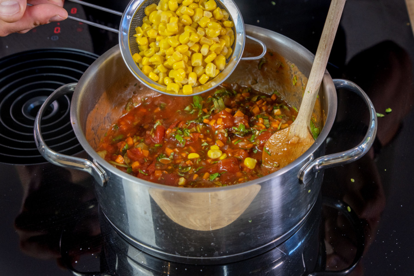 Mais zur Tomatensauce für den Tortellini-Auflauf geben