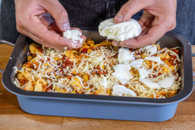Käase auf dem Tortellini-Auflauf mit Tomatensauce verteilen
