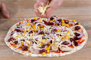 Käse über die Blitzpizza streuen