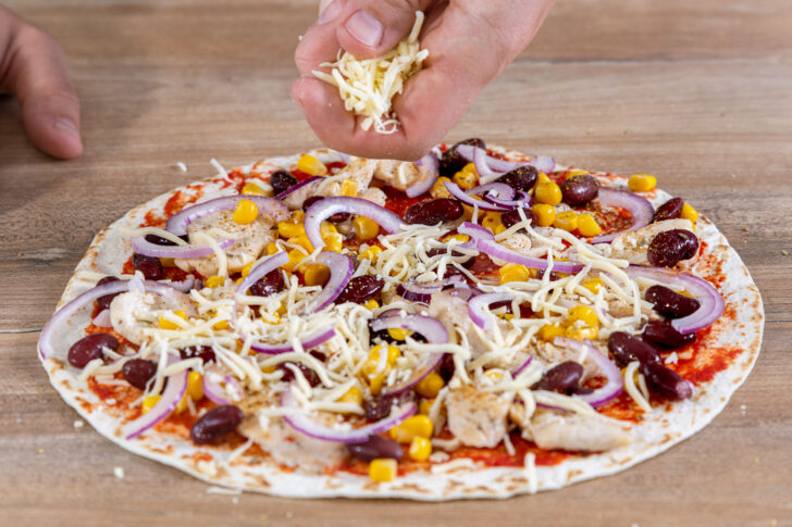 Käse über die Blitzpizza streuen