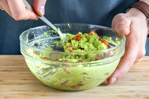 Tomaten unter den Avocadoaufstrich rühren