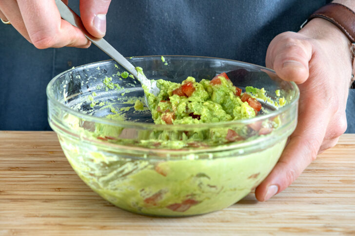 Tomaten unter den Avocadoaufstrich rühren