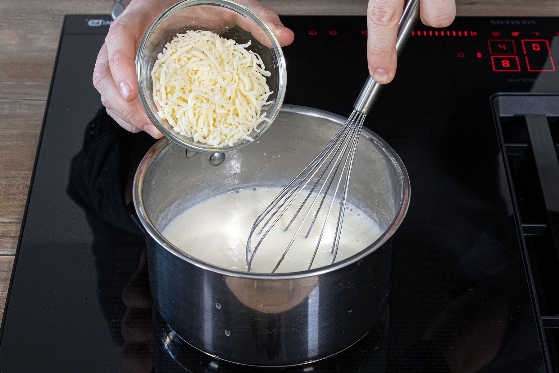 Käse unter die Béchamelsauce mischen