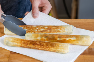 ausgebackene Filoteig-Rollen mit Spinat und Feta auf Küchenpapier abtropfen lassen