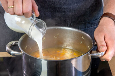 Sahne zur Kürbissuppe geben