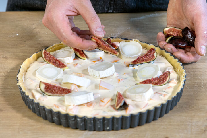 Feigen und Ziegenkäse auf der Kürbisquiche verteilen