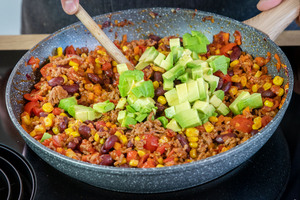 Avocado mit in die Pfanne für die Hackfleischmasse der mexikanischen Tacos geben