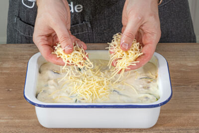 Käse über die Moussaka streuen