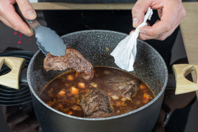 Fleisch und Gewürzbeutel in den Fond geben