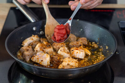 Tomatenmark zum Fleisch geben