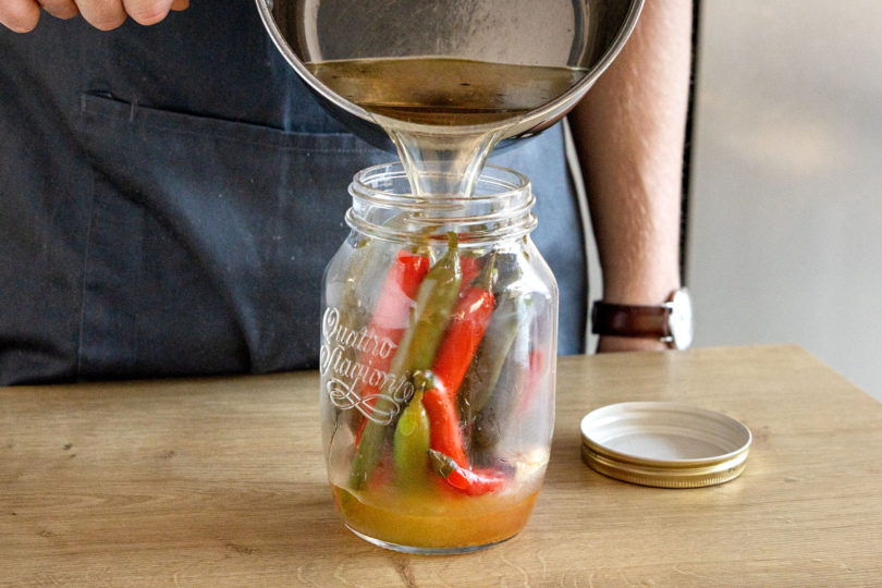 Peperoni im Glas mit Flüssigkeit auffüllen