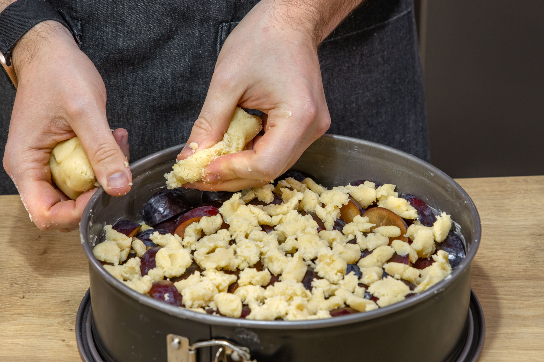 Streusel auf Pflaumenkuchen verteilen