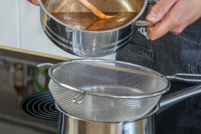 Portweinsauce über Sieb gießen