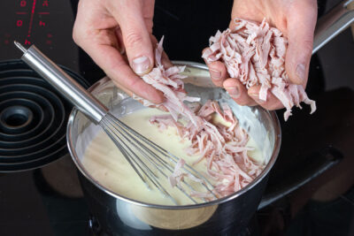 Schinken und Käse zur Soße geben