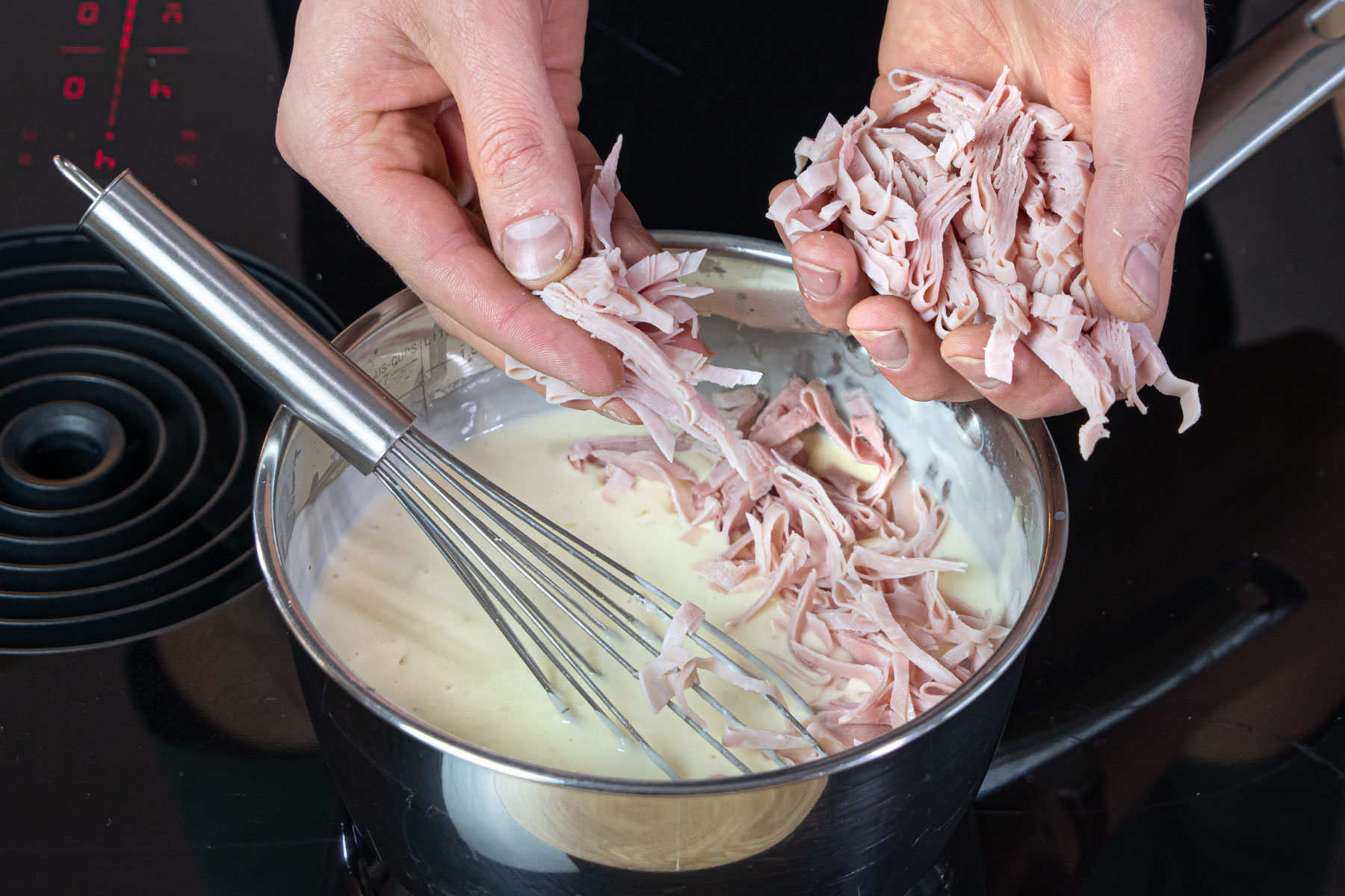 Schinken und Käse zur Soße geben