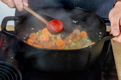 Tomatenmark zu dem Gemüse geben