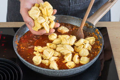 Tortellini in die Hackfleischsauce geben