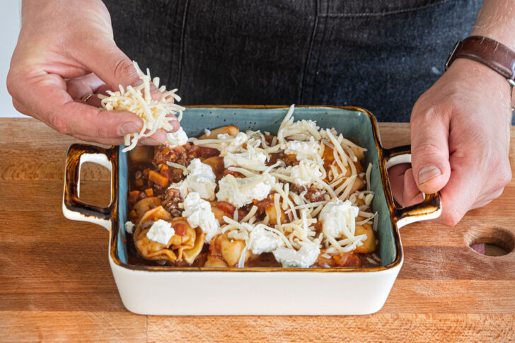 Ricotta und Gouda über die Tortellini in Hackfleischsauce geben