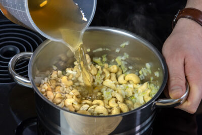 Gemüsebrühe zu Cashews gießen